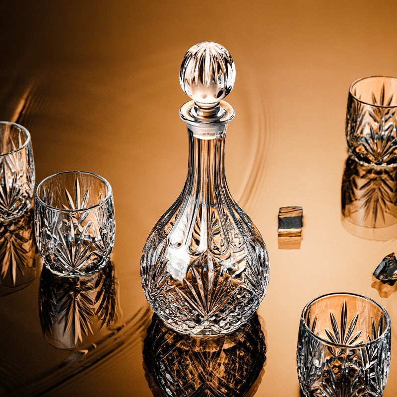Crystal decanter and glasses on a reflective surface with a warm background