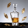 Glass decanter with whiskey and gold leaves on a dark surface