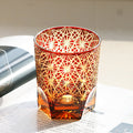 Decorative glass candle holder with geometric pattern on a white surface