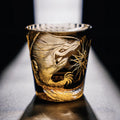 Gold embossed dragon design on a glass against a dark background