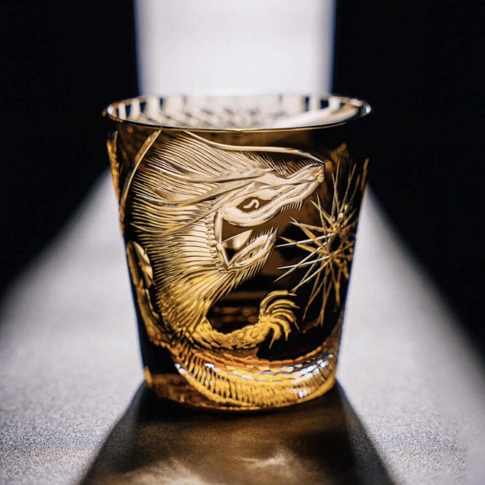 Gold embossed dragon design on a glass against a dark background
