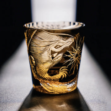 Gold embossed dragon design on a glass against a dark background