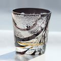 Decorative glass tumbler with intricate patterns on a light background