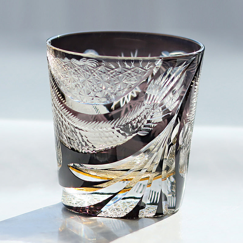 Decorative glass tumbler with intricate patterns on a light background