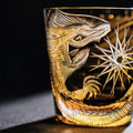Decorative glass with intricate gold engravings of a dragon and floral design on a dark background