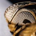 Close-up of a gold ring with intricate design on a light gray background
