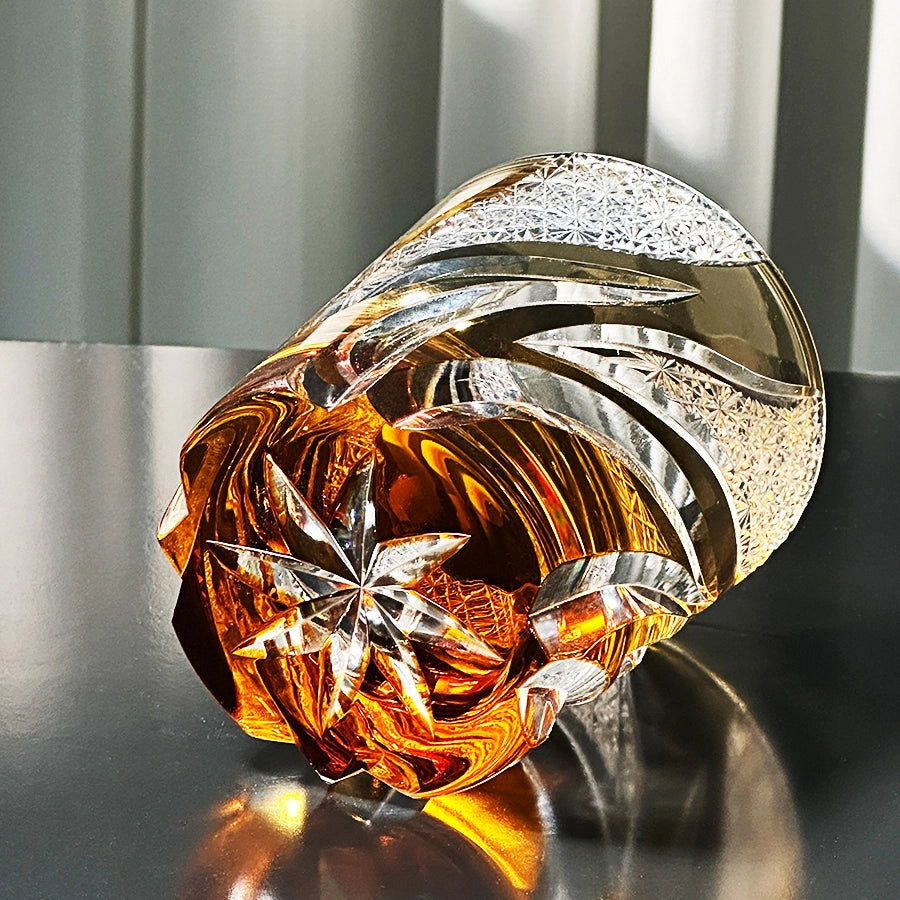 Decorative glass piece with gold and silver colors on a reflective surface