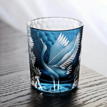 Decorative glass tumbler with blue design on a wooden surface