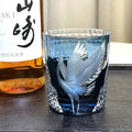 Decorative glass with engraved design next to a bottle of Suntory Hakushu whisky.