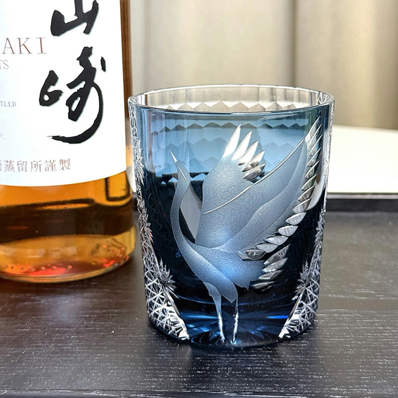 Decorative glass with engraved design next to a bottle of Suntory Hakushu whisky.