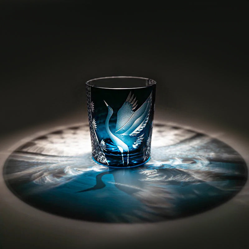 Decorative glass cup with engraved design on a dark surface