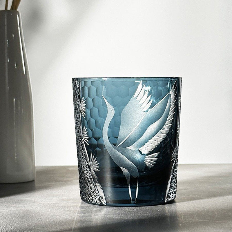 Decorative glass candle holder with angel design on a wooden surface.
