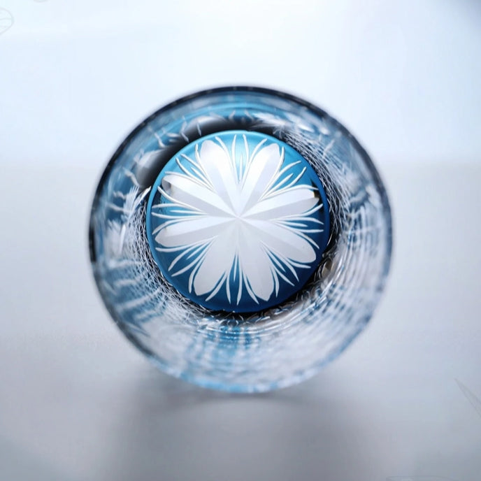 Close-up of a blue bottle cap with a white floral design on a white background