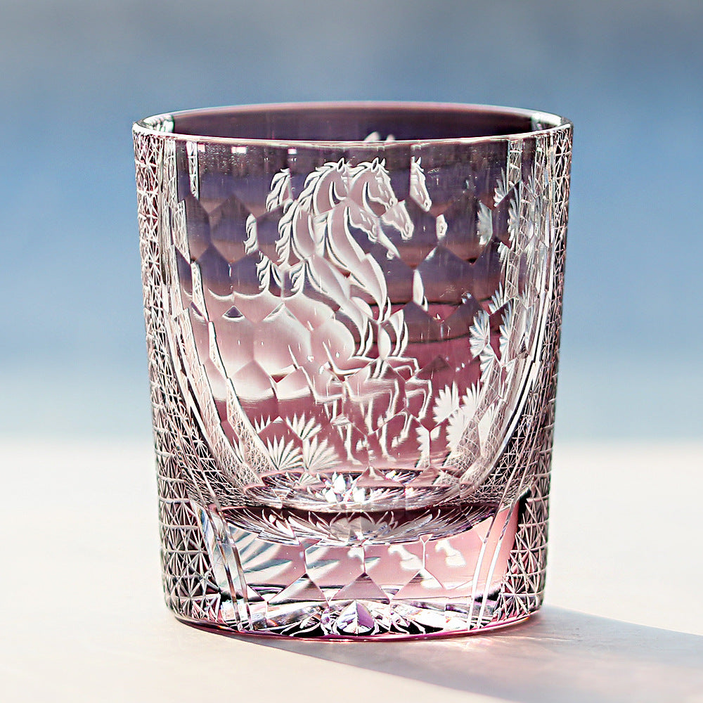 Crystal tumbler with horse etching on a light blue background