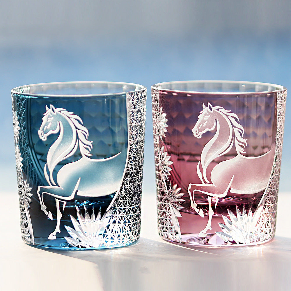 Two glass tumblers with horse designs on a blurred background