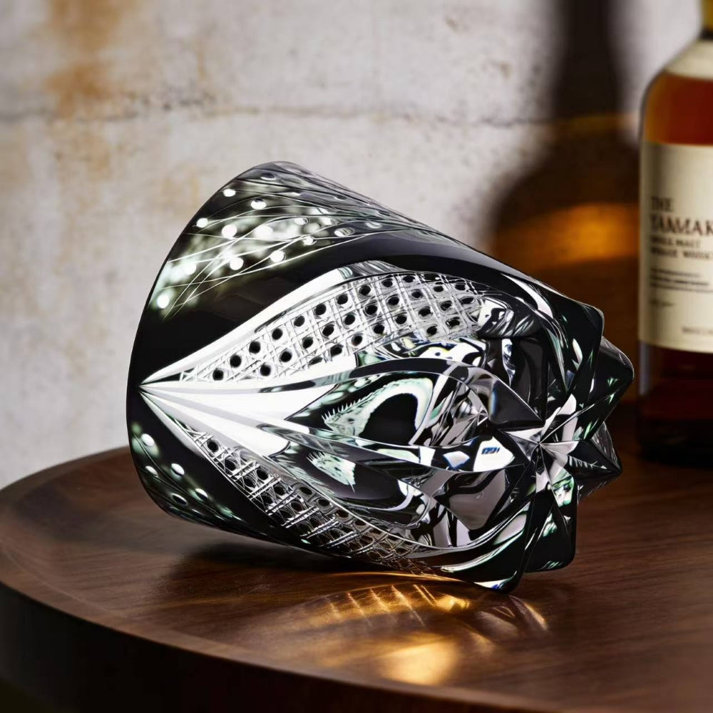 Decorative glass piece on a wooden surface with a bottle in the background