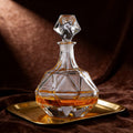 Glass decanter with a diamond-shaped stopper on a gold tray against a brown background