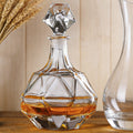 Glass decanter with geometric design filled with liquid on a wooden surface.