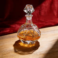 Crystal decanter with geometric design on a wooden surface with a red fabric background